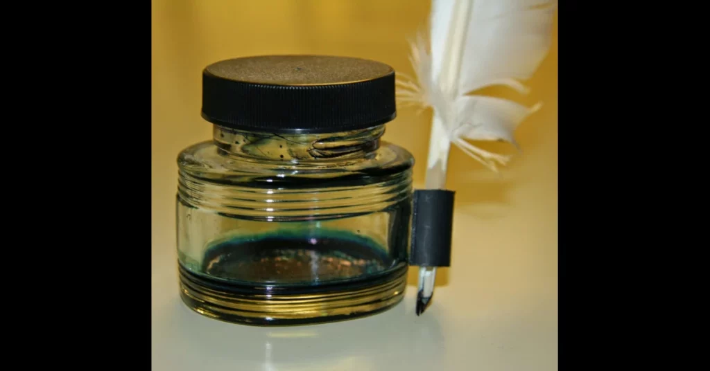 un flascó buit de tinta i una ploma per escriure
