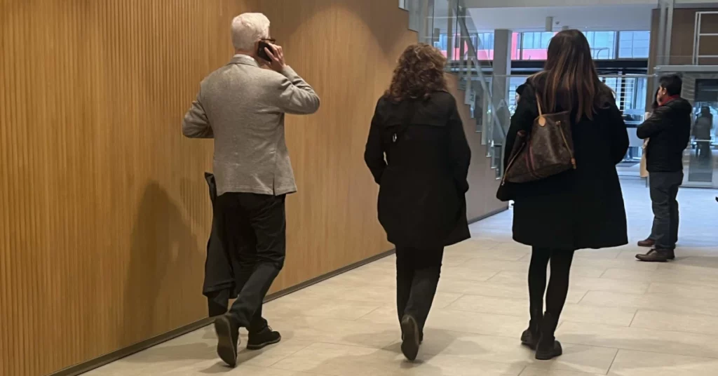 tres persones d'esquena camine en un edifici de justicia