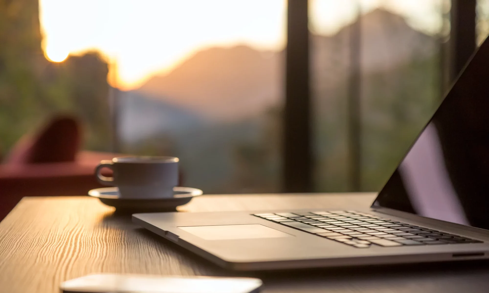 "Computer Coffee Mug and Telephone on black wood table sun rising"