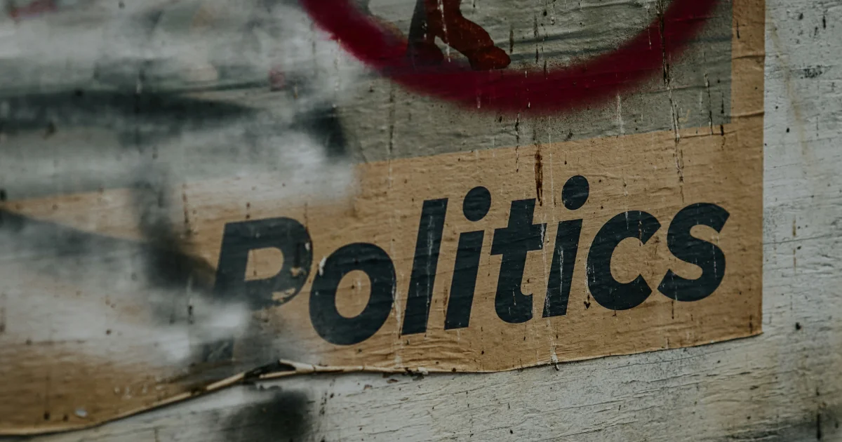 Cartell pegat a paret amb la paraula Politics