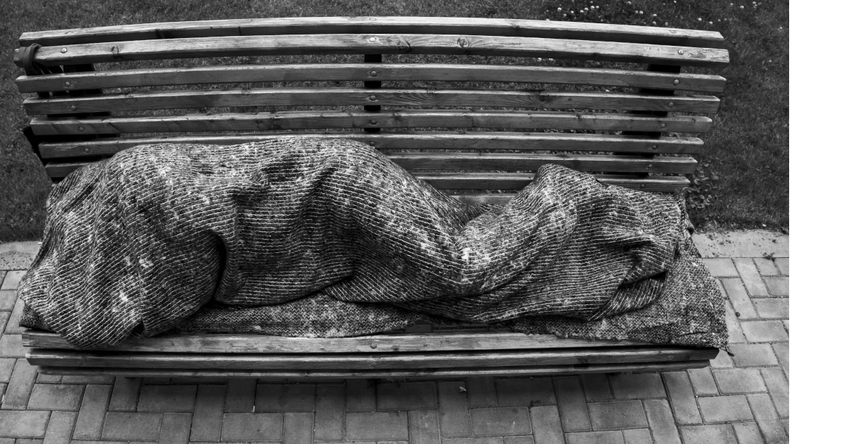 persona dorm en un banc públic